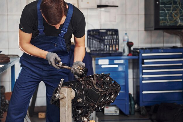 Reparador profissional na garagem trabalha com motor de automóvel quebrado