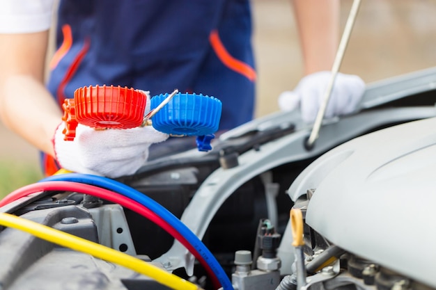 Reparador que sostiene la herramienta del monitor para verificar y reparar el sistema de aire acondicionado del automóvil Técnico que verifica la recarga de refrigerante del sistema de aire acondicionado del automóvil Reparación de aire acondicionado