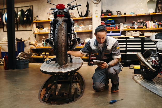 Un reparador serio examinando una motocicleta