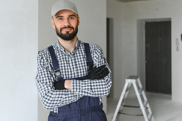 Reparador sonriente de pie cerca de la escalera y mirando a la cámara