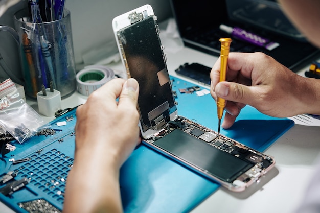 Reparador de teléfonos inteligentes quitando tornillos