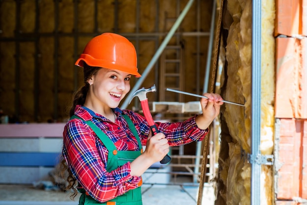 Foto reparador en uniforme futuro ingeniero niño feliz uso martillo reparación herramienta edificio construcción sitio niño arquitecto trabajador día del trabajo concepto desarrollo infantil adolescente niña asistente