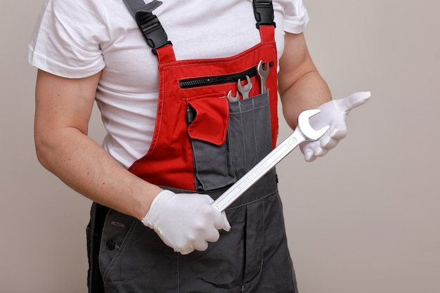 Foto reparador vistiendo un mono rojo y gris, sosteniendo una llave en la mano