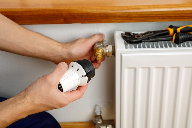 Reparar el radiador de calefacción closeup hombre reparando el radiador con una llave extrayendo el aire del radiador