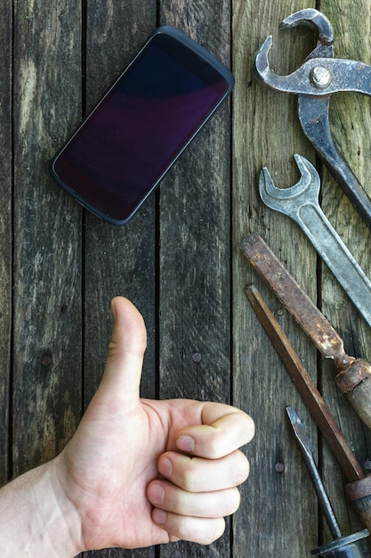 Reparar el teléfono usando herramientas Antiguo taller con nuevas tecnologías Antecedentes del trabajo de carpintería Aprobación del trabajo con el pulgar hacia arriba