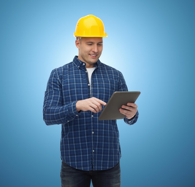 reparatur-, bau-, gebäude-, menschen- und wartungskonzept - lächelnder männlicher baumeister oder arbeiter im helm mit tablet-pc-computer über blauem hintergrund