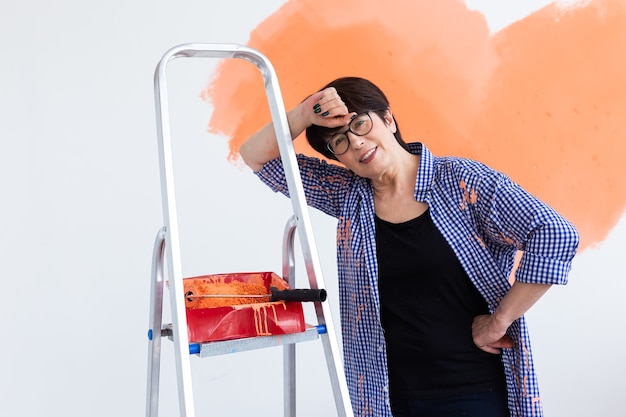 Reparatur in der Wohnung. Glückliche Frau mittleren Alters malt die Wand mit Farbe.