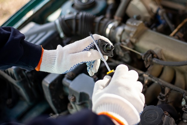 Reparatur unter der Motorhaube eines Autos mit behandschuhten Händen und einem Schraubendreher-Automechaniker bei workxA