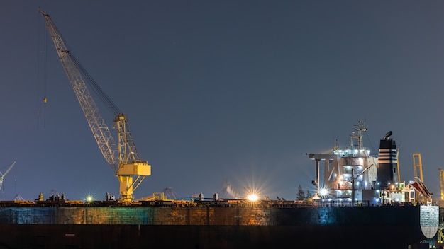 Reparatur von Containerölschiffen in der Werft nachts. Kann für Versand- oder Transportkonzept verwendet werden.