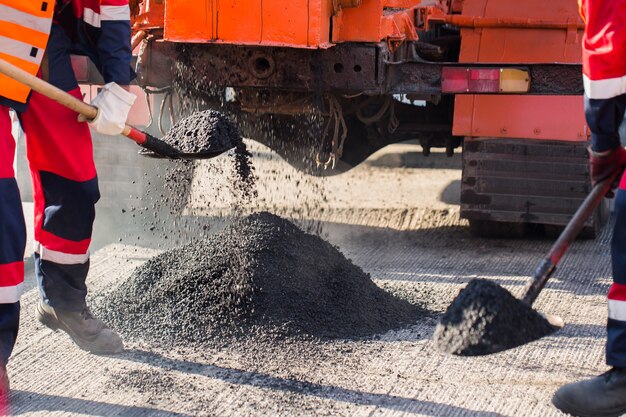 Reparatur von Straßen, Autobahnen und Gehwegen. Patchen. Das Arbeiten mit einer Schaufel schläft in der Grube ein