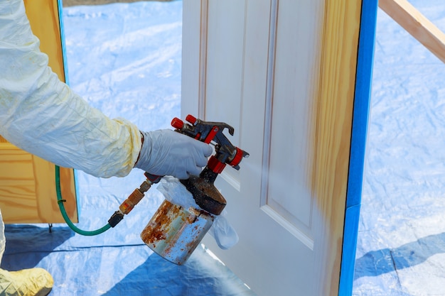 Reparo de casa pintar a porta de madeira na cor branca com um spray