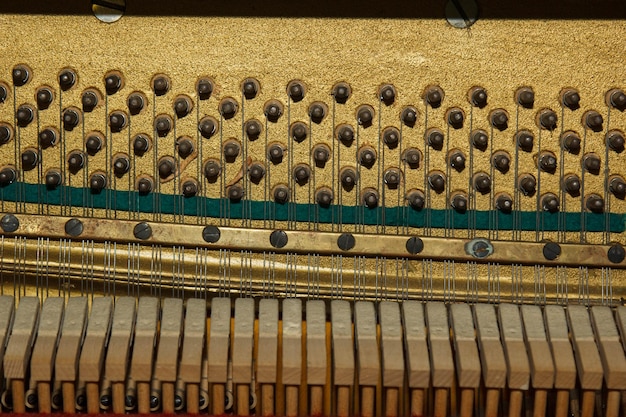 Reparo de um instrumento musical de cordas o interior de um piano com cordas de latão e um martelo de madeira instrumento musical antiquado para tocar música