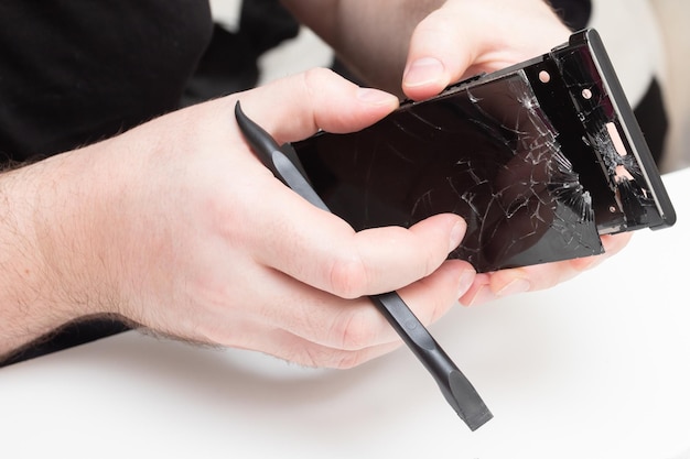Reparo do telefone celular O assistente remove o vidro protetor da tela de um smartphone