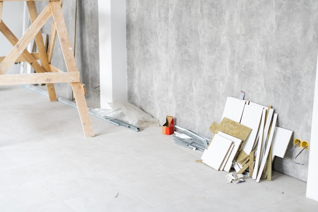 Reparo no apartamento. a cabra do pintor no interior de uma sala iluminada com paredes rebocadas frescas. paredes brancas em uma casa de construção civil.