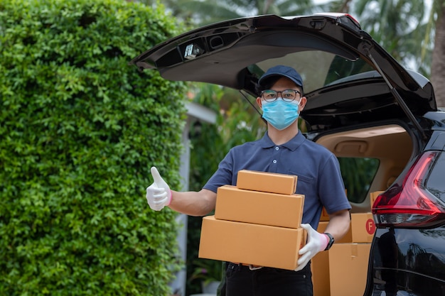 Repartidor asiático empleado en gorra azul camiseta uniforme máscara guante mantenga Parcel box. servicio conceptual del virus de coronavirus pandémico en cuarentena [Covid-19]