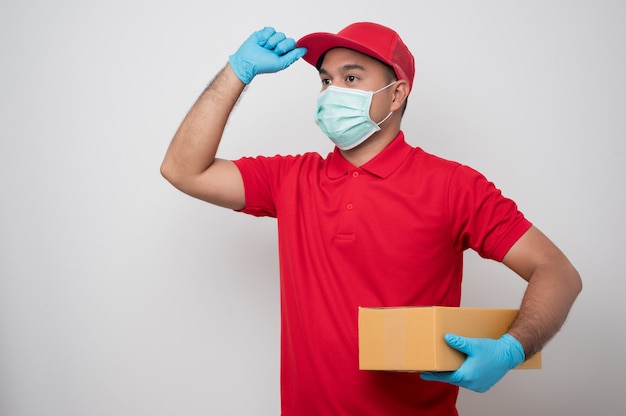 Repartidor asiático joven en uniforme con máscara protectora y guantes de goma