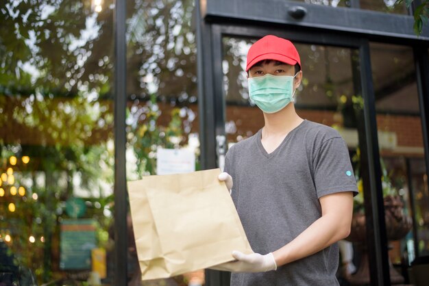 Un repartidor asiático lleva mascarilla y sostiene una bolsa de supermercado