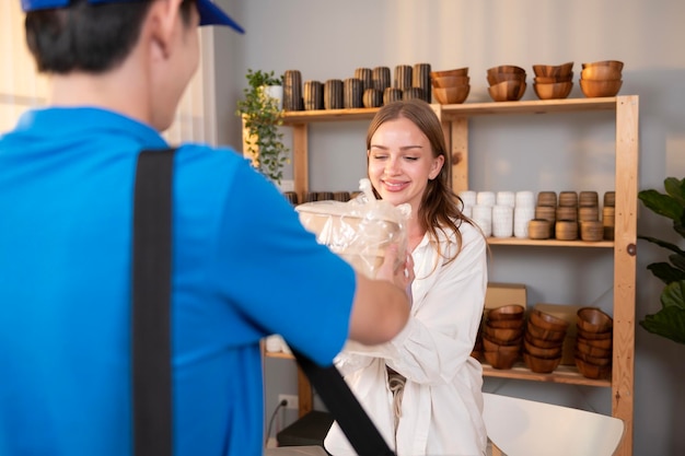 Un repartidor asiático con uniforme azul que envía comida a una joven cliente en su tienda