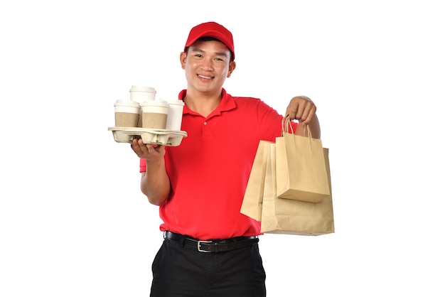 Repartidor asiático en uniforme rojo lleva bolsas de comida y bebida en manos aisladas sobre fondo blanco.