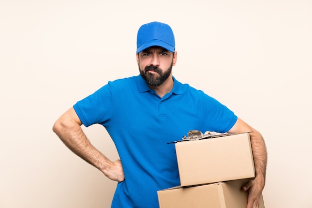 Repartidor con barba sobre pared aislada enojado