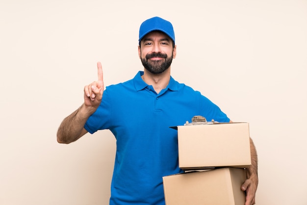 Repartidor con barba sobre pared aislada mostrando y levantando un dedo en señal de lo mejor