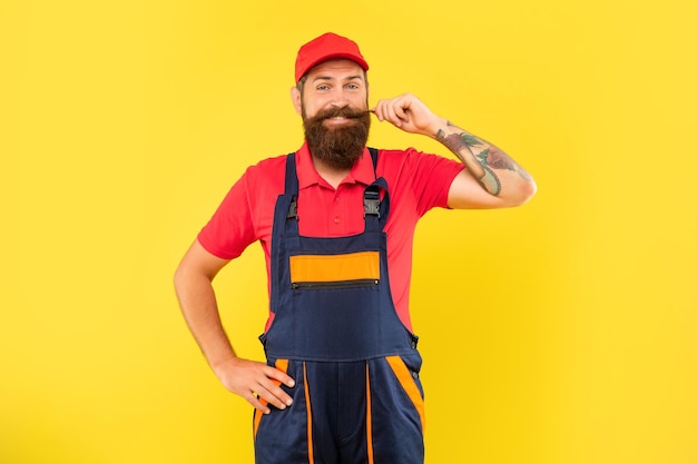 Repartidor barbudo alegre en ropa de trabajo sobre fondo amarillo