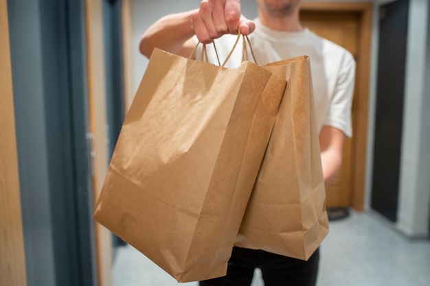 Repartidor con bolsa de papel con comida en la entrada El mensajero entrega la caja con verduras y frutas frescas al cliente