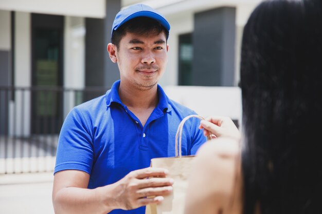 Foto repartidor en una camiseta azul con paquete de alimentos