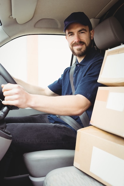 Repartidor conduciendo su camioneta con paquetes en el asiento delantero