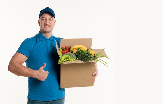 Repartidor dando pulgares y sosteniendo la caja de supermercado