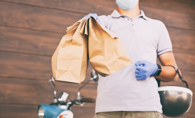 El repartidor entrega la comida al cliente en su ciclomotor.