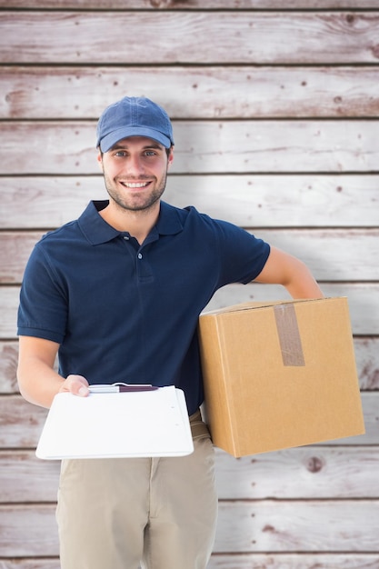 Foto repartidor feliz con caja de cartón y portapapeles contra tablones de madera