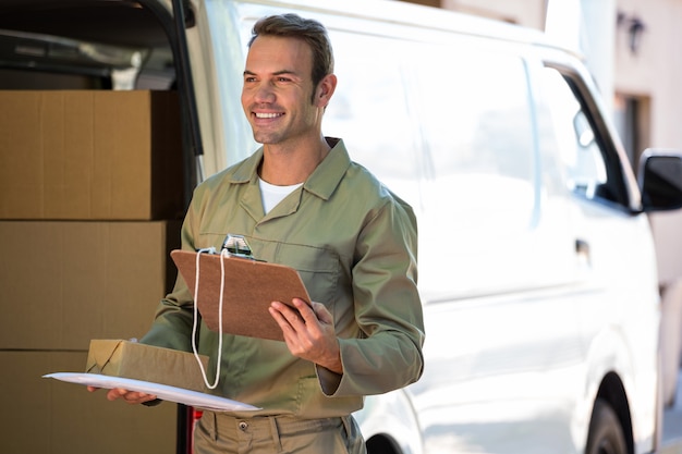 Repartidor feliz con caja de cartón y portapapeles