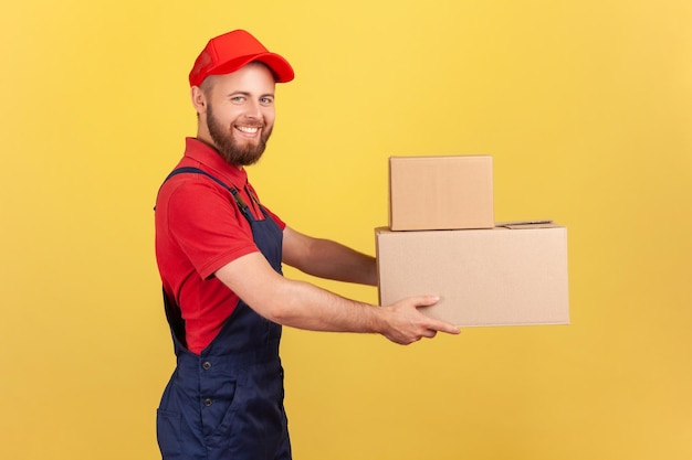 Repartidor feliz sosteniendo dos cajas de cartón entregando pedidos puerta a puerta