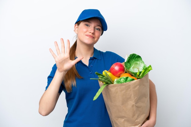 Repartidor joven tomando una bolsa de comida para llevar aislada sobre fondo blanco contando cinco con los dedos