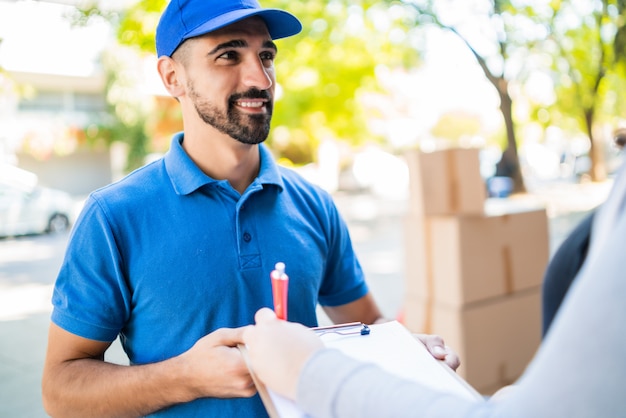 Foto repartidor llevando paquetes al hacer la entrega a domicilio.