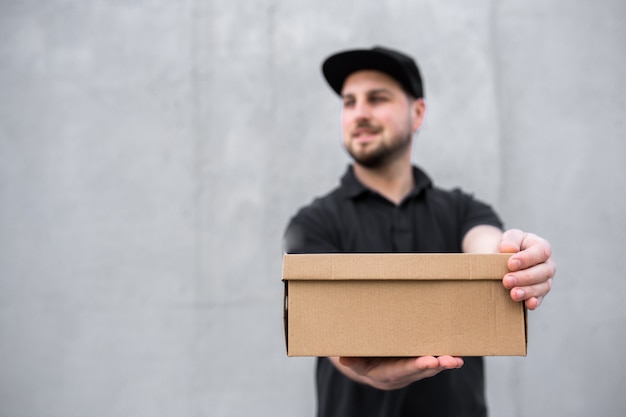 Repartidor masculino en uniforme negro con paquete