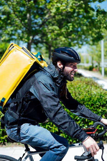 Repartidor con mochila amarilla en bicicleta