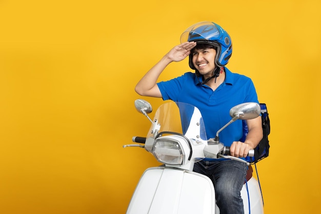 Repartidor montando motocicleta y caja de entrega aislada sobre fondo amarillo