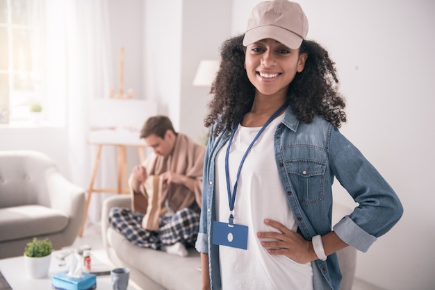 Repartidor. Mujer agradable alegre mirándote mientras trabaja como mensajero para una empresa de servicios de entrega