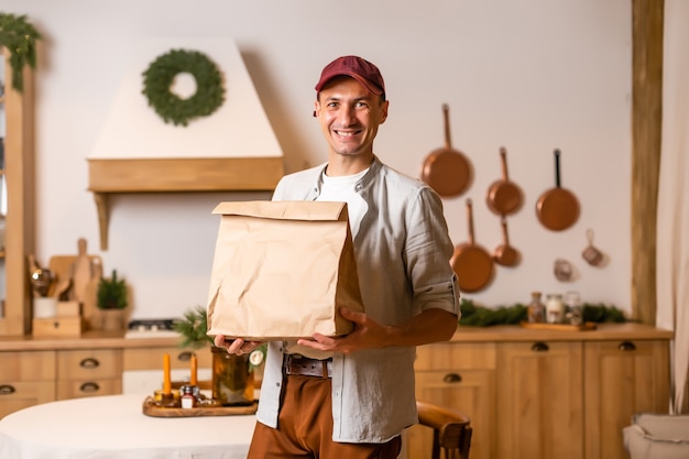 Un repartidor con un paquete de comida se encuentra en un interior de Navidad