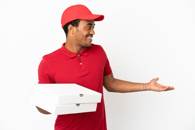 Repartidor de pizza afroamericana recogiendo cajas de pizza sobre una pared blanca aislada con expresión de sorpresa mientras mira de lado