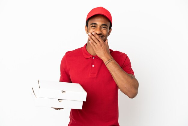 Repartidor de pizza afroamericana recogiendo cajas de pizza sobre pared blanca aislada feliz y sonriente cubriendo la boca con la mano