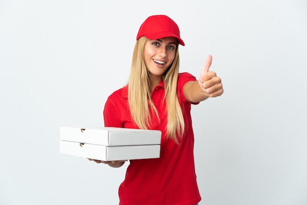 Repartidor de pizza mujer sosteniendo una pizza aislada en la pared blanca con los pulgares hacia arriba porque algo bueno ha sucedido