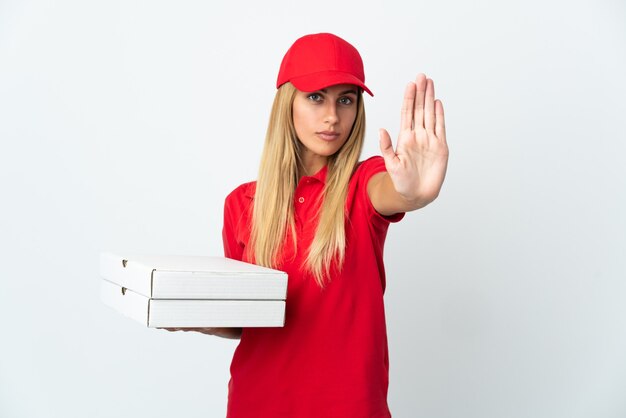 Repartidor de pizza mujer sosteniendo una pizza aislado sobre fondo blanco haciendo gesto de parada