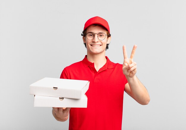 Repartidor de pizza a un niño sonriendo y mirando amigablemente, mostrando el número dos o el segundo con la mano hacia adelante, contando hacia atrás