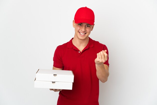 Repartidor de pizza con uniforme de trabajo recogiendo cajas de pizza aislado en la pared blanca haciendo gesto de dinero