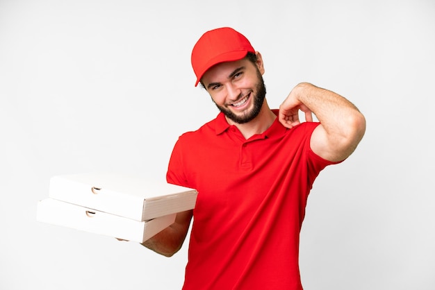 Repartidor de pizza con uniforme de trabajo recogiendo cajas de pizza sobre fondo blanco aislado riendo