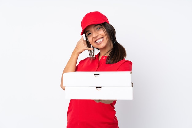Repartidor de pizzas joven sobre fondo blanco aislado haciendo gesto de teléfono y apuntando hacia el frente