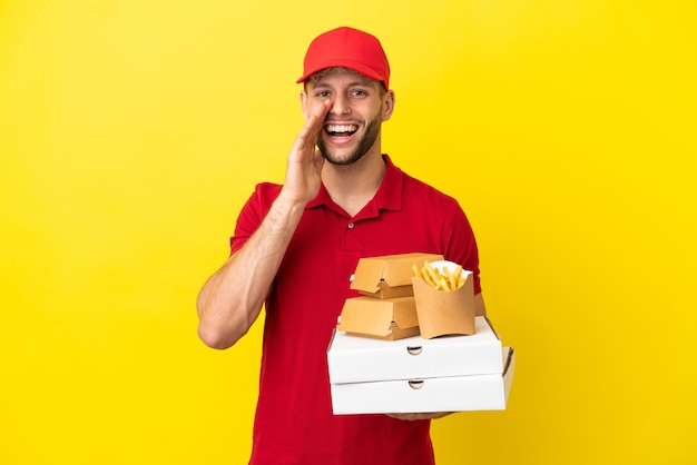 Repartidor de pizzas recogiendo cajas de pizza y hamburguesas sobre antecedentes aislados gritando con la boca abierta